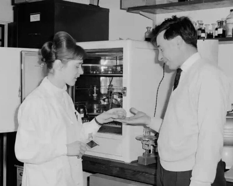 Old black and white photo of man and woman in lab.