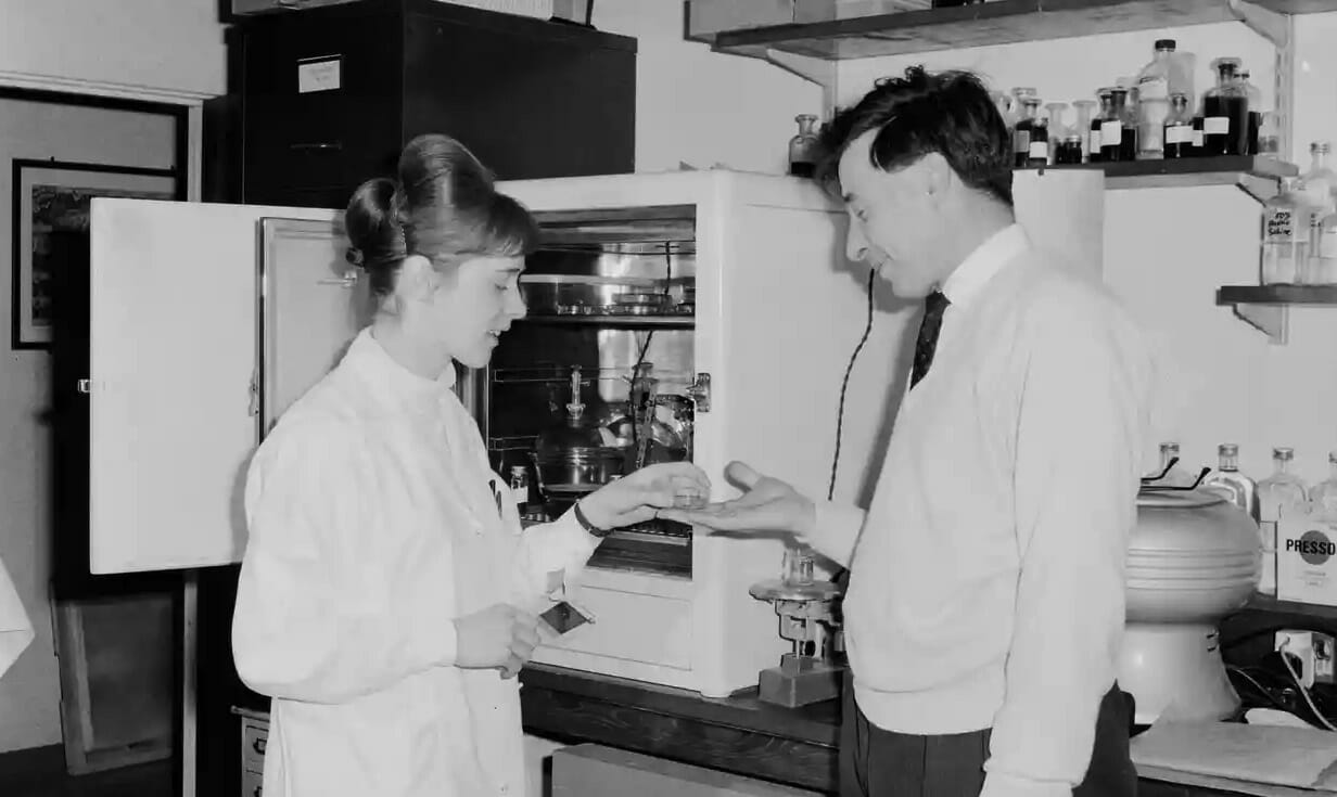 Old black and white photo of man and woman in lab.